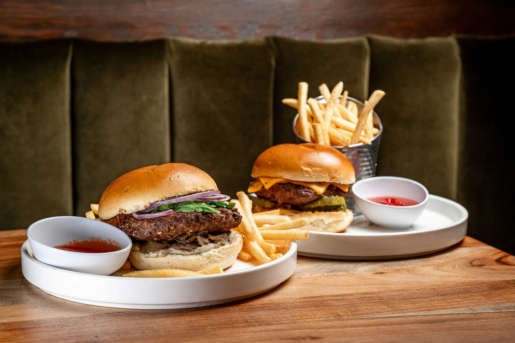 Two burgers with fries on a restaurant table